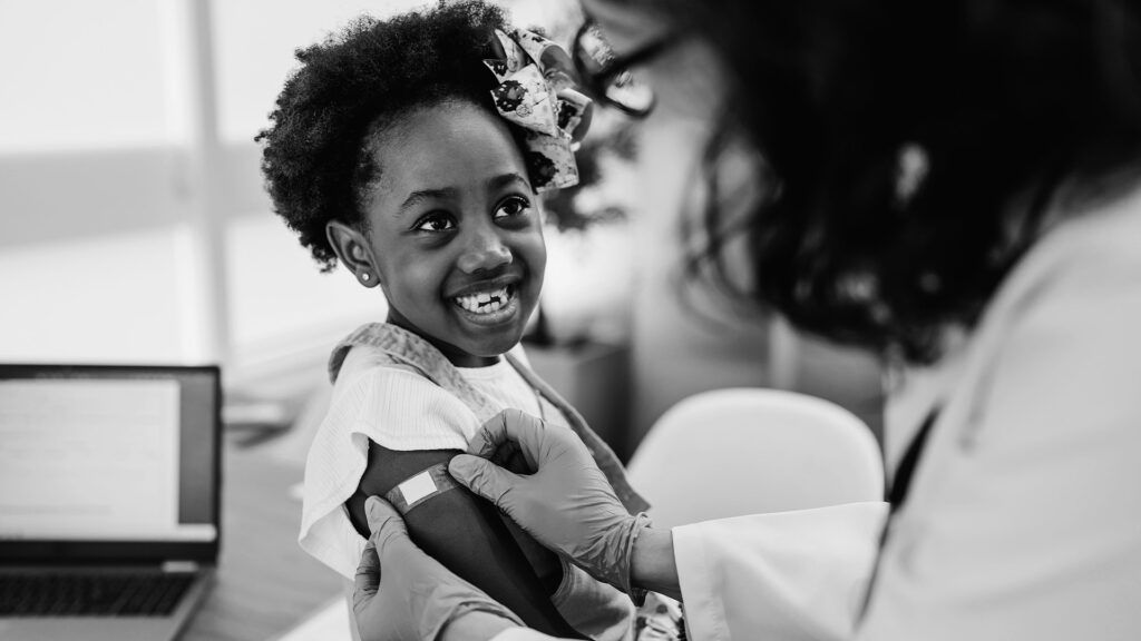 Czarne dziecko otrzymuje w gabinecie lekarskim szczepionkę przeciw grypie w ramię