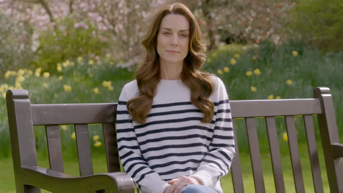 Kate Middleton w białym topie w granatowe paski siada na ławce i ogłasza, że ​​ma raka
