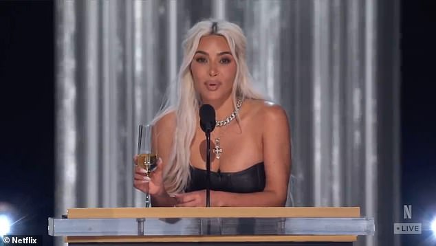 Kim, trzymając kieliszek szampana, miała blond włosy
