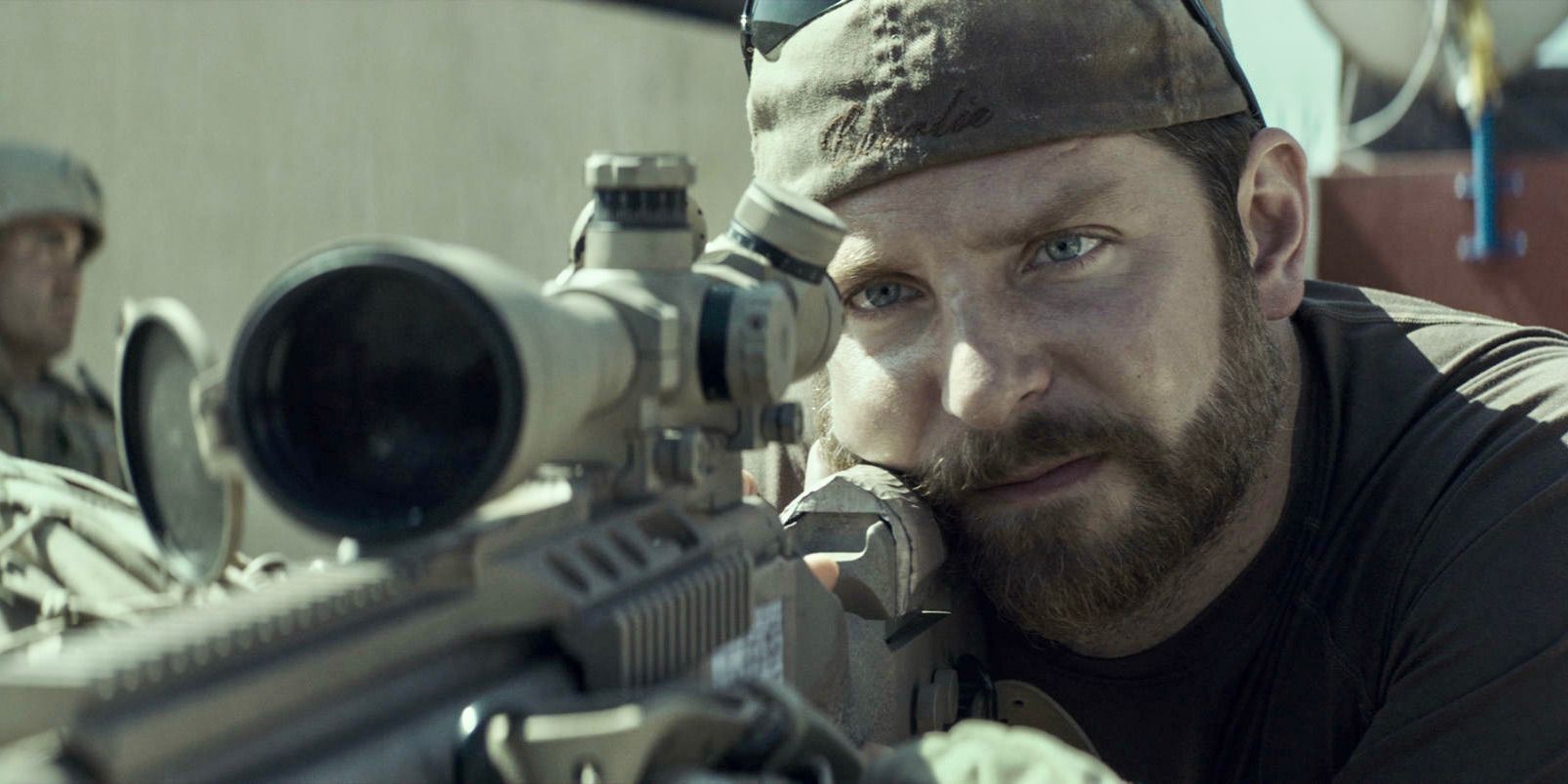 Bradley Cooper jako Chris Kyle celujący z karabinu snajperskiego w filmie American Sniper