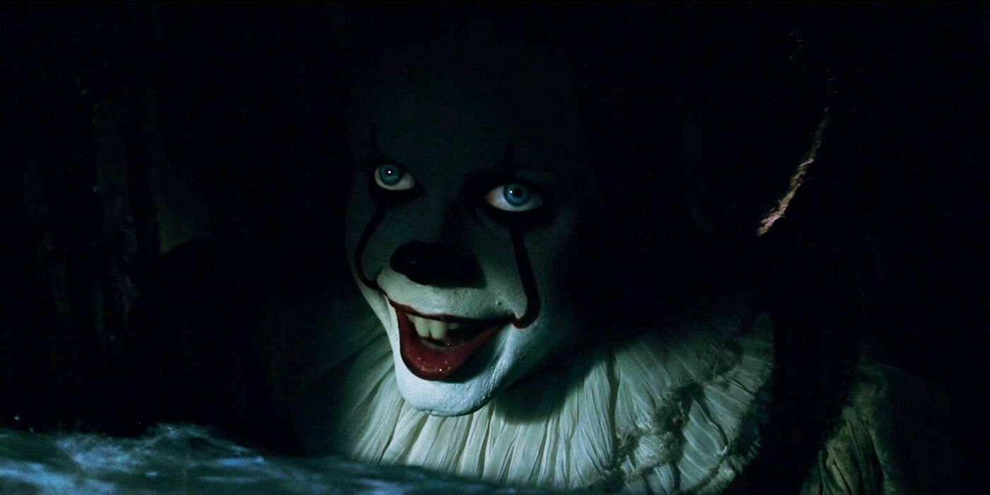 Bill Skarsgård jako Pennywise uśmiechający się w cieniu kanalizacji w horrorze It z 2017 roku