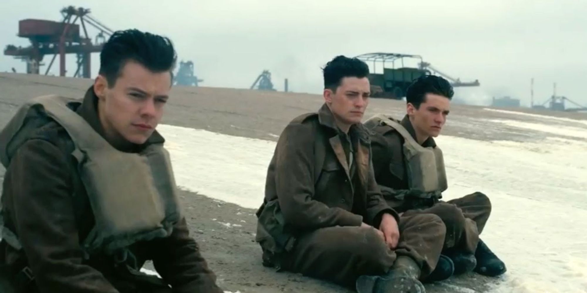 Harry Styles, Aneurin Barnard i Fionn Whitehead siedzą na plaży w Dunkierce