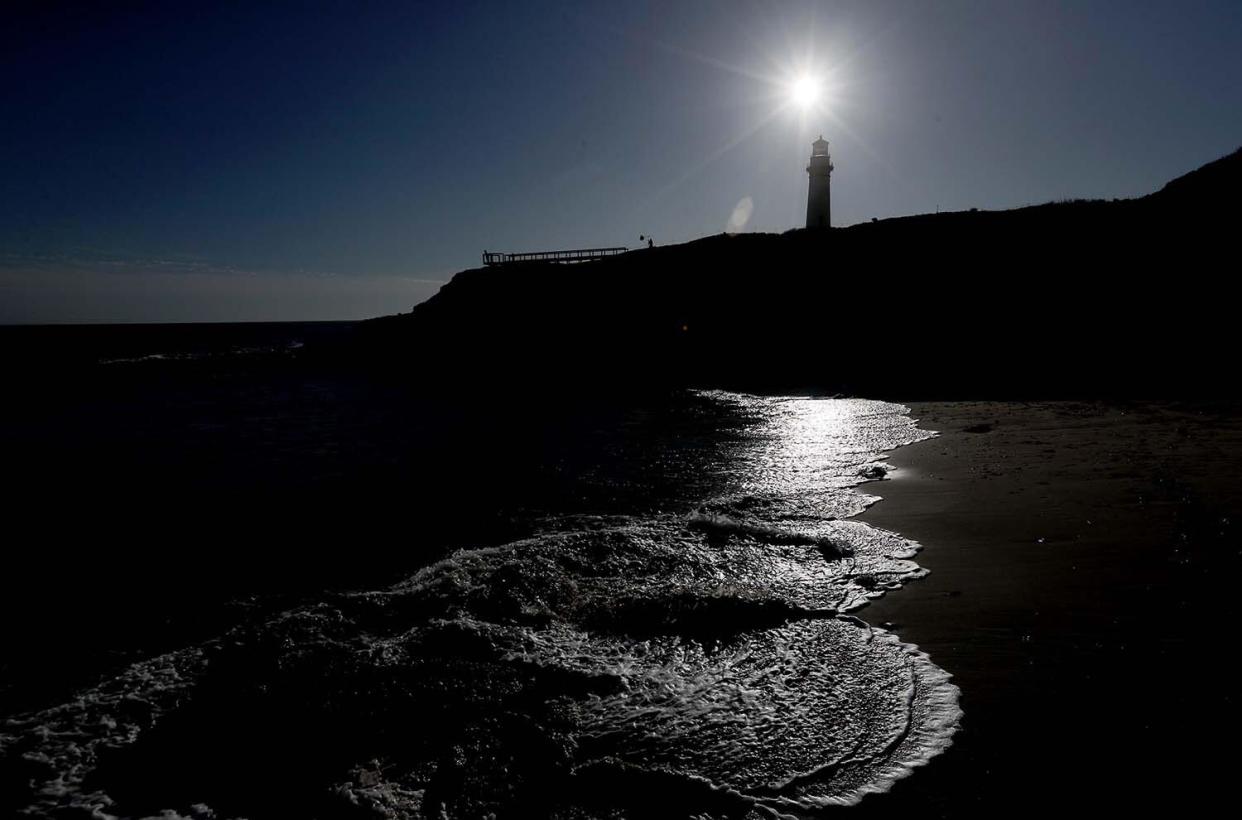 Słońce zachodzi za latarnią morską Pigeon Point na wybrzeżu hrabstwa San Mateo.