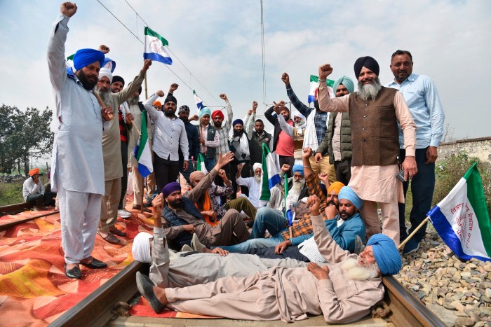 Protestujący rolnicy wykrzykują hasła, siedząc na torach kolejowych, aby zablokować pociągi w pobliżu Amritsar w Indiach, niedziela, 10 marca