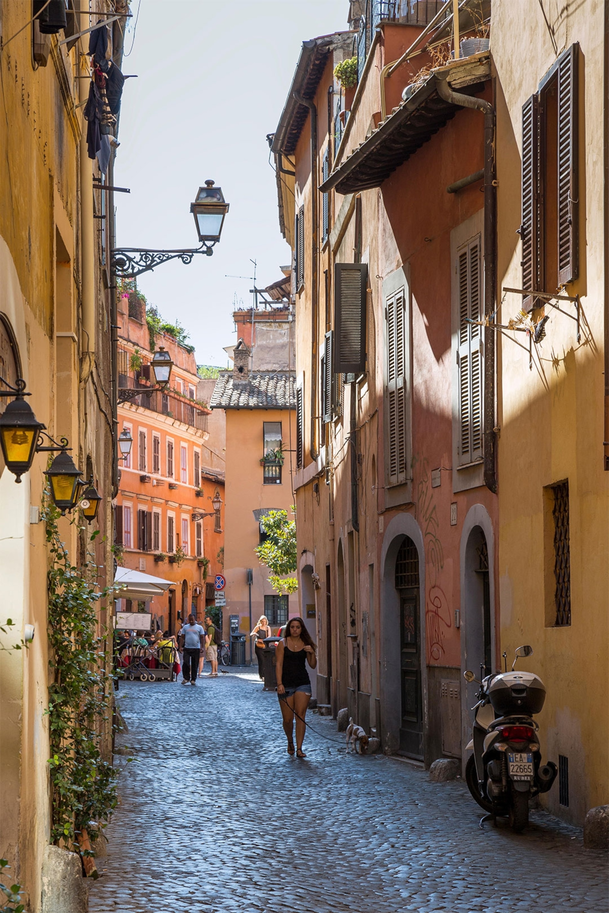 Kobieta idzie ciasną uliczką na Trastevere w Rzymie.