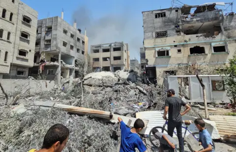 Reuters Palestyńczycy przeprowadzają inspekcję domu zniszczonego podczas izraelskiego strajku w związku z izraelską operacją wojskową w ramach konfliktu między Izraelem a Hamasem w obozie dla uchodźców Nuseirat w środkowej Strefie Gazy