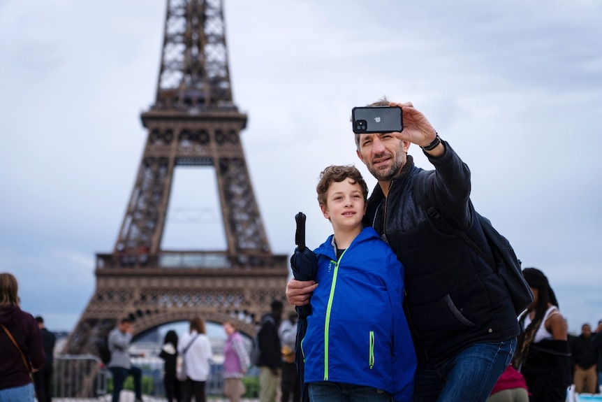 Młody chłopak i mężczyzna pozują do zdjęcia w pobliżu Wieży Eiffla 