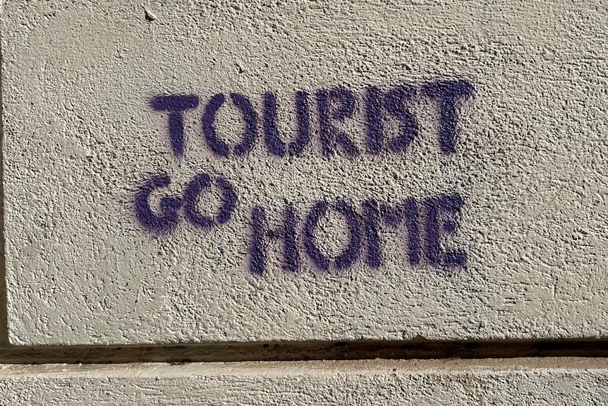 Na kamiennym murze napisano szablonem graffiti "Turysta idź do domu".