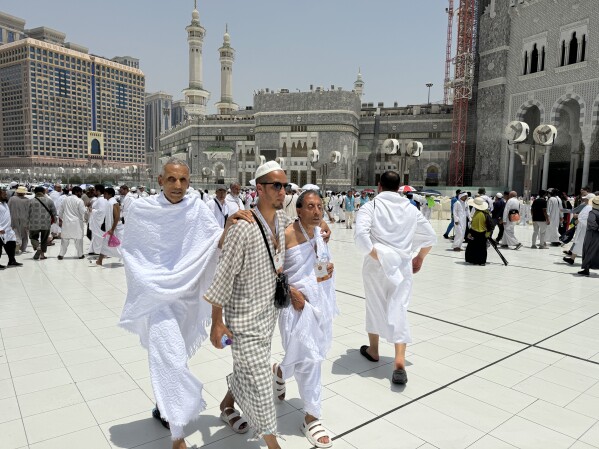 Dwóch niewidomych pielgrzymów odprawia pielgrzymkę z pomocą przewodnika przed Wielkim Meczetem podczas corocznej pielgrzymki do Mekki w Arabii Saudyjskiej, czwartek, 13 czerwca 2024 r. (AP Photo/Baraa Anwer)