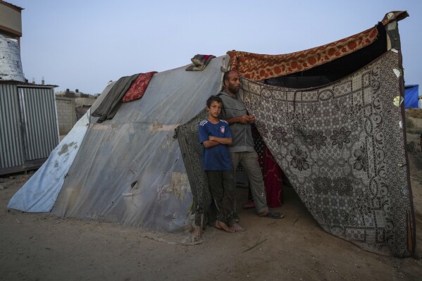 Abdelsattar al-Batsh stoi ze swoim synem przed świętem Id al-Adha w Deir al Balah w Strefie Gazy, wtorek, 11 czerwca 2024 r. Zostali wysiedleni ze swojego domu w wyniku wojny między Izraelem a Hamasem.  (AP Photo/Abdel Kareem Hana)