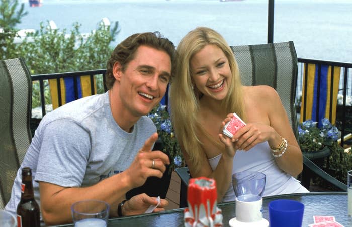 Matthew McConaughey i Kate Hudson śmieją się, grając w karty przy stole na świeżym powietrzu nad wodą w scenie z filmu "Jak stracić faceta w 10 dni"