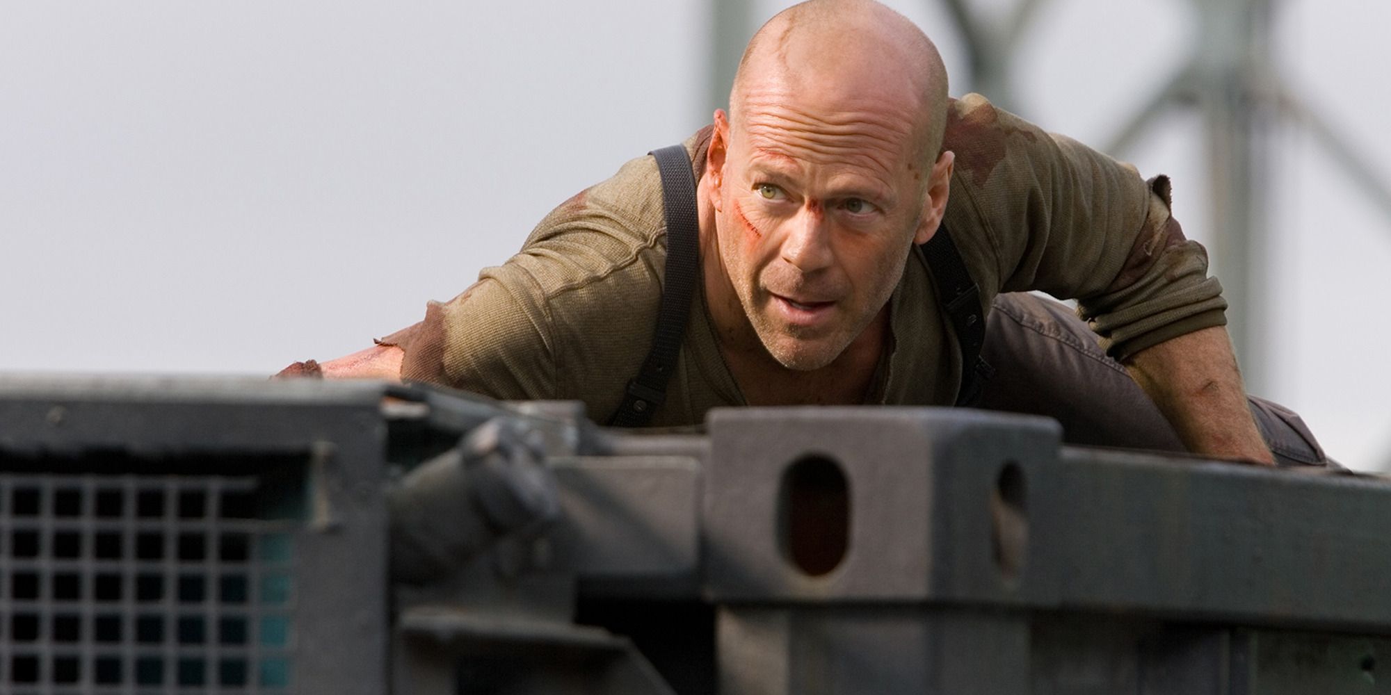 Bruce Willis ukrywający się przed kimś na szczycie metalowej konstrukcji w grze Live Free or Die Hard