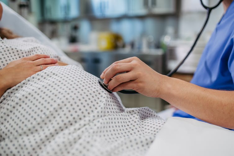 Lekarz trzymający stetoskop na brzuchu osoby w ciąży