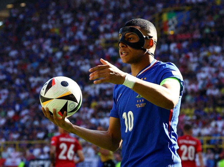 Piłkarz w masce ochronnej na nos wrzuca piłkę do gry podczas meczu.