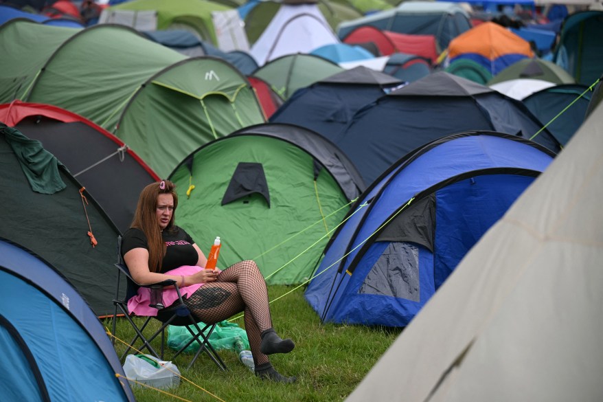 Uczestnik festiwalu siedzący przy namiotach podczas trzeciego dnia festiwalu Glastonbury w Worthy Farm w Somerset w Anglii