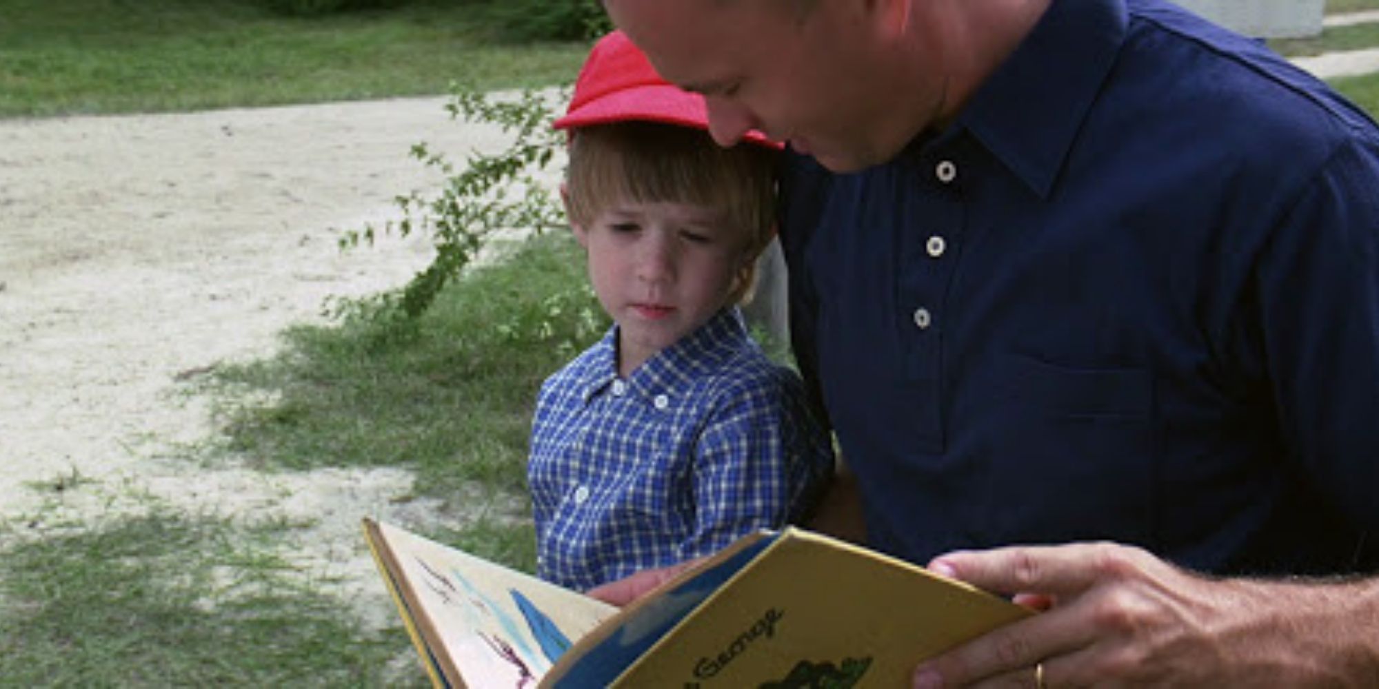 Forrest Gump czyta książkę Forrestowi Juniorowi na zewnątrz w Forrest Gump.
