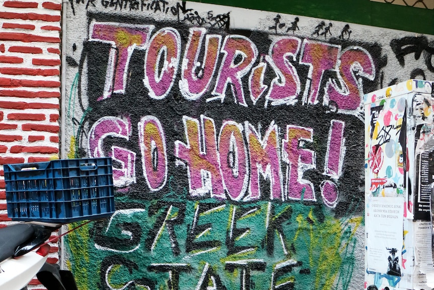 Graffiti na ścianie w Atenach z napisem "Turyści wracają do domu, państwo greckie zabija".