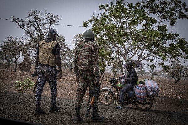 PLIK – Funkcjonariusz policji i żołnierz z Beninu zatrzymują motocyklistę na punkcie kontrolnym pod Porgą w Beninie, 26 marca 2022 r. Bojownicy dżihadu, którzy od dawna działali w niestabilnym afrykańskim regionie Sahelu, osiedlili się w północno-zachodniej Nigerii po przekroczeniu granicy z sąsiedniego Beninu, nowego Jak stwierdzono w raporcie ze środy, 19 czerwca 2024 r., jest to najnowszy trend w przemieszczaniu się bojowników do bogatszych krajów przybrzeżnych Afryki Zachodniej.  (AP Photo/Marco Simoncelli, plik)