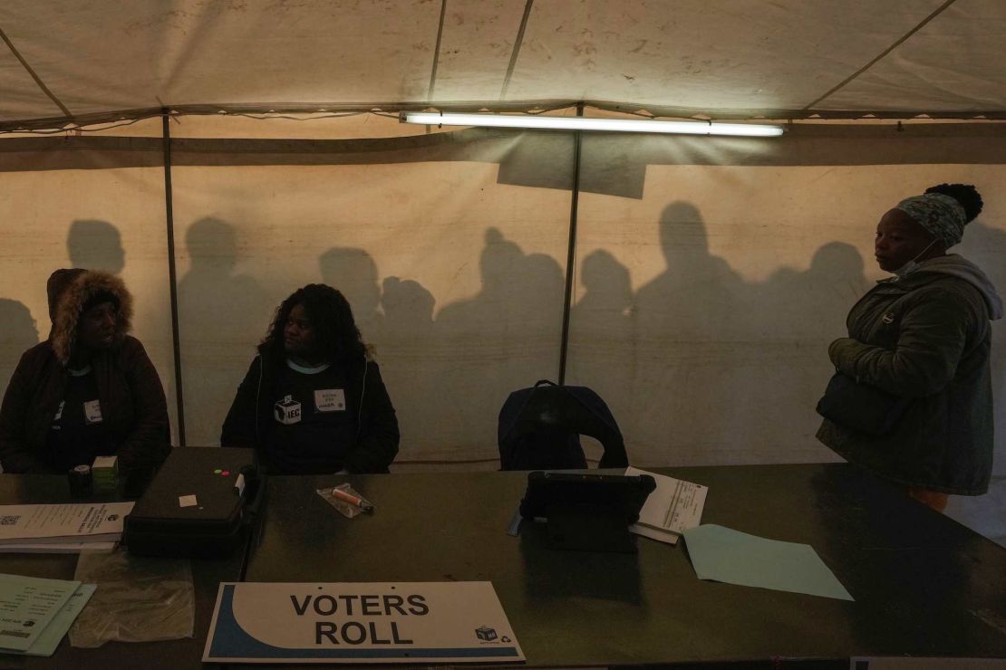 Pracownicy wyborczy przygotowują się do otwarcia lokalu wyborczego, podczas gdy wyborcy ustawiają się w kolejce, aby oddać głos w wyborach powszechnych w Aleksandrze niedaleko Johannesburga w Republice Południowej Afryki, środa, 29 maja 2024 r. (AP Photo/Themba Hadebe)