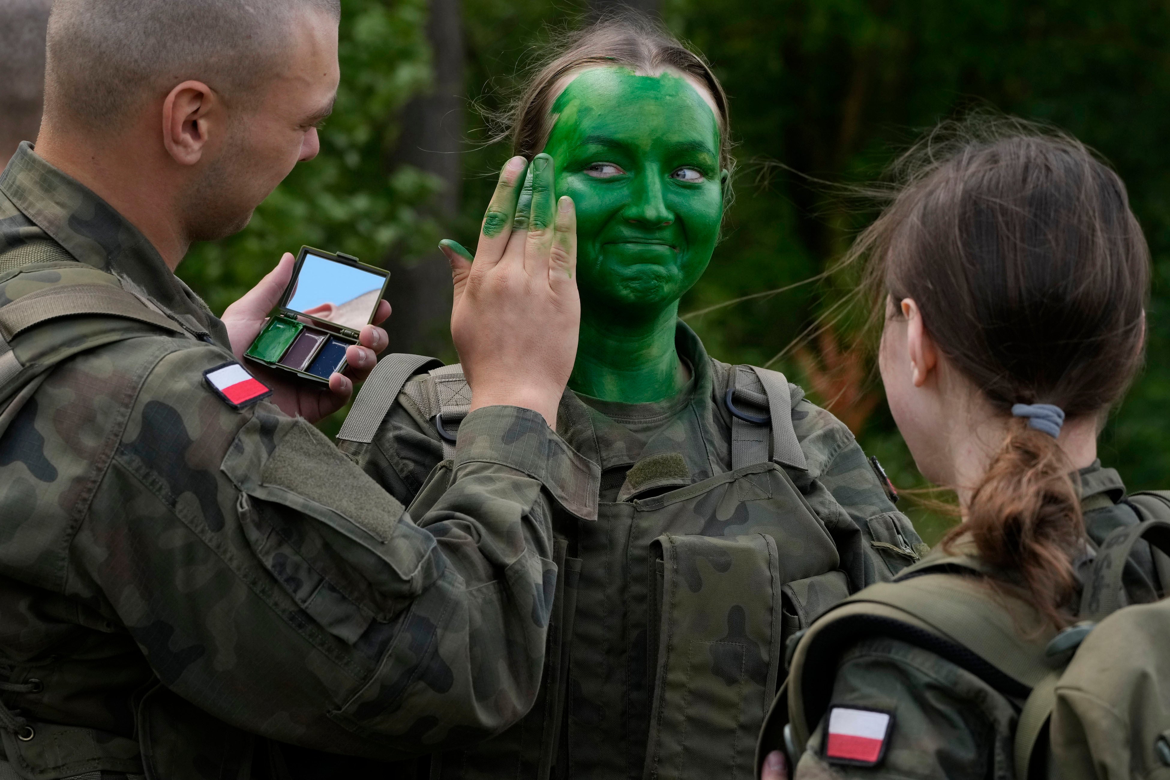 Ochotnicy polskiej armii uczą się malować twarz kamuflażem podczas podstawowego szkolenia w Nowogrodzie w Polsce