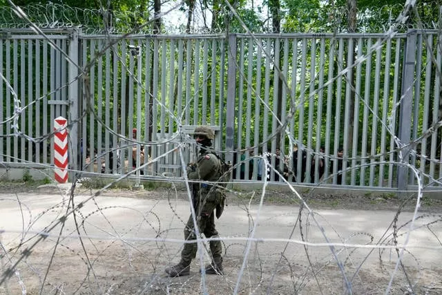 Polski żołnierz patroluje metalową barierę na granicy z Białorusią