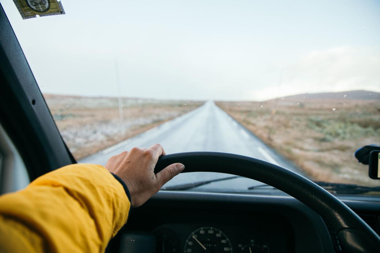 Kobieta trzyma kierownicę starego samochodu kempingowego na pustej górskiej drodze.  Otwarte horyzonty i nieskończone możliwości, koncepcja wycieczki samochodowej.  Konwersja kampera