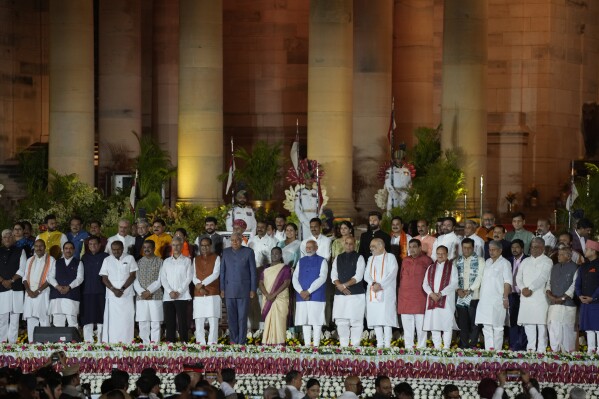 Wiceprezydent Indii Jagdeep Dhankhar (centrolewy), prezydent Indii Draupadi Murmu (w środku) i premier Indii Narendra Modi w niebieskiej kamizelce pozują do grupowego zdjęcia z nowo zaprzysiężonym ministrem podczas ceremonii zaprzysiężenia w indyjskim pałacu prezydenckim w New Delhi, Indie, niedziela, 9 czerwca 2024 r. (AP Photo/Manish Swarup)