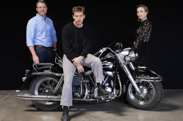 Jeff Nichols, po lewej, scenarzysta i reżyser "Rowerzyści," pozuje z członkami obsady Austinem Butlerem (w środku) i Jodie Comer, czwartek, 30 maja 2024 r. w Los Angeles.  Motocykl to Harley Davidson Pan Head z 1965 r., na którym Butler jechał w filmie.  (AP Photo/Chris Pizzello)