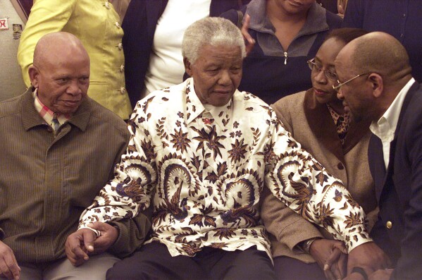 PLIK – Były prezydent Republiki Południowej Afryki i przywódca Afrykańskiego Kongresu Narodowego (ANC) Nelson Mandela (w środku) zostaje powitany w Johannesburgu 18 lipca 2003 r. podczas obchodów swoich 85. urodzin.  Republika Południowej Afryki przeżywa moment głębokich rozmyślań po wyborach, które doprowadziły do ​​drastycznego rozłamu w AKN, tej samej partii, która 30 lat temu zapewniła krajowi wolność i demokrację.  (AP Photo/Themba Hadebe, plik)