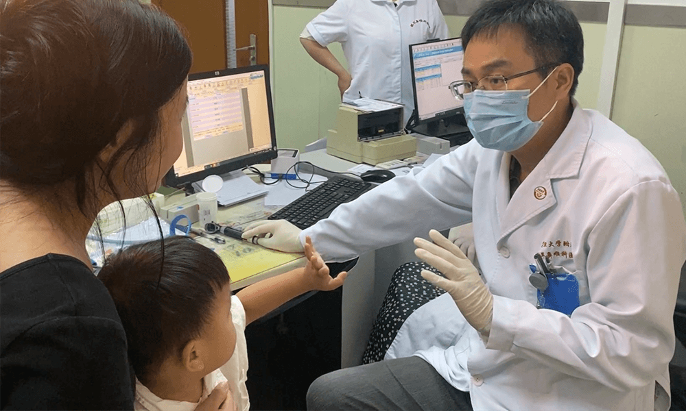 Doktor Yilai Shu komunikuje się z młodym pacjentem szpitala okulistycznego i laryngologicznego Uniwersytetu Fudan.