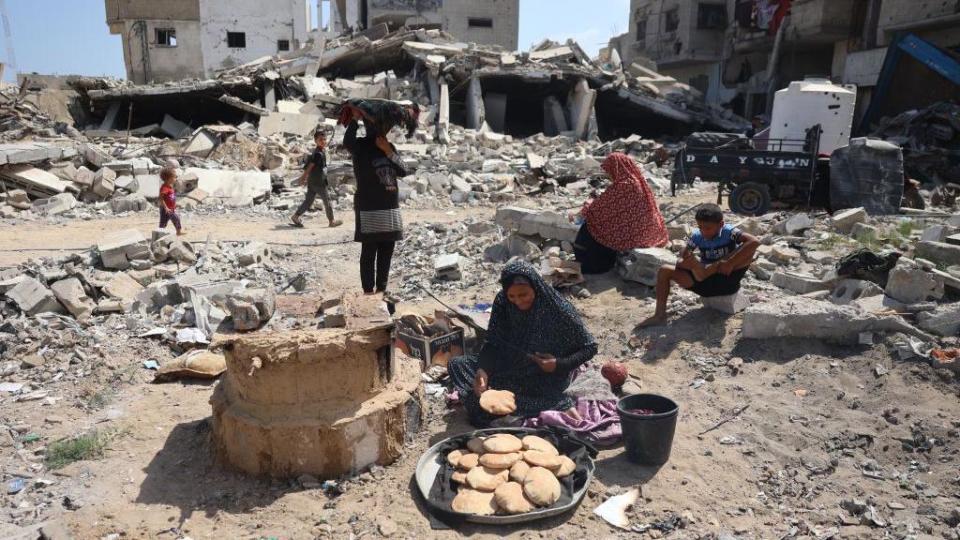 Palestyńska kobieta piecze chleb pośród gruzów zniszczonych budynków w południowym mieście Gazy, Chan Junus (30 czerwca 2024 r.)