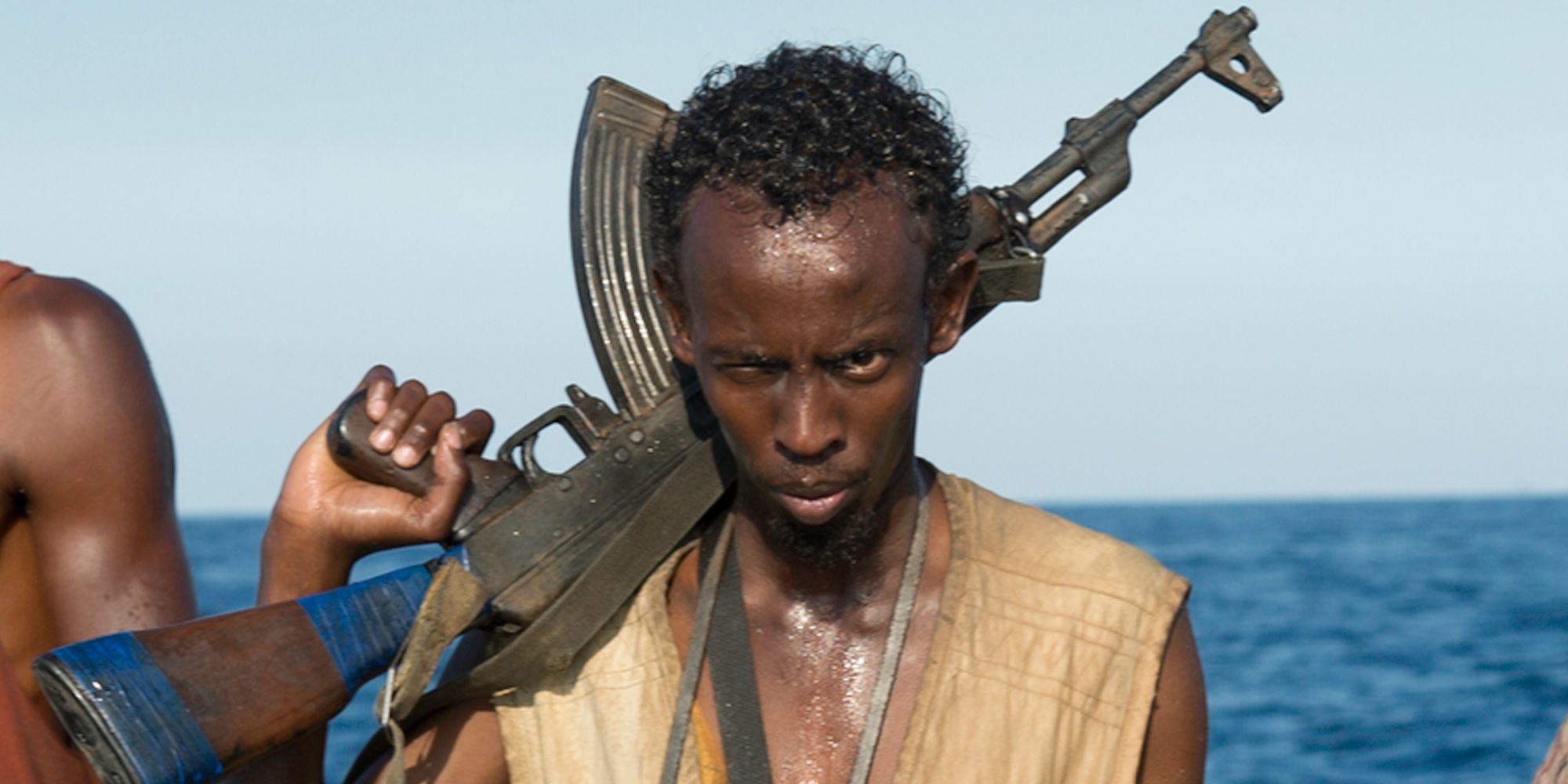 Barkhad Abdi w roli kapitana Phillipsa trzymającego karabin AK-47