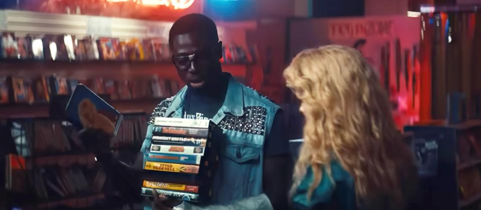 Moses Sumney, grający Leona w filmie Maxxxine, niesie po sklepie naręcze kaset wideo.