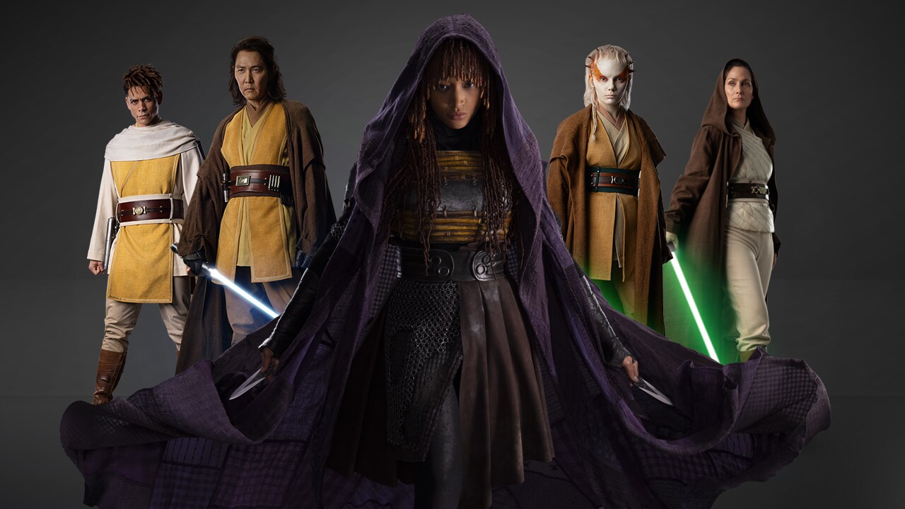 Pięć postaci ubranych w stroje science fiction, z których dwie trzymają miecze świetlne