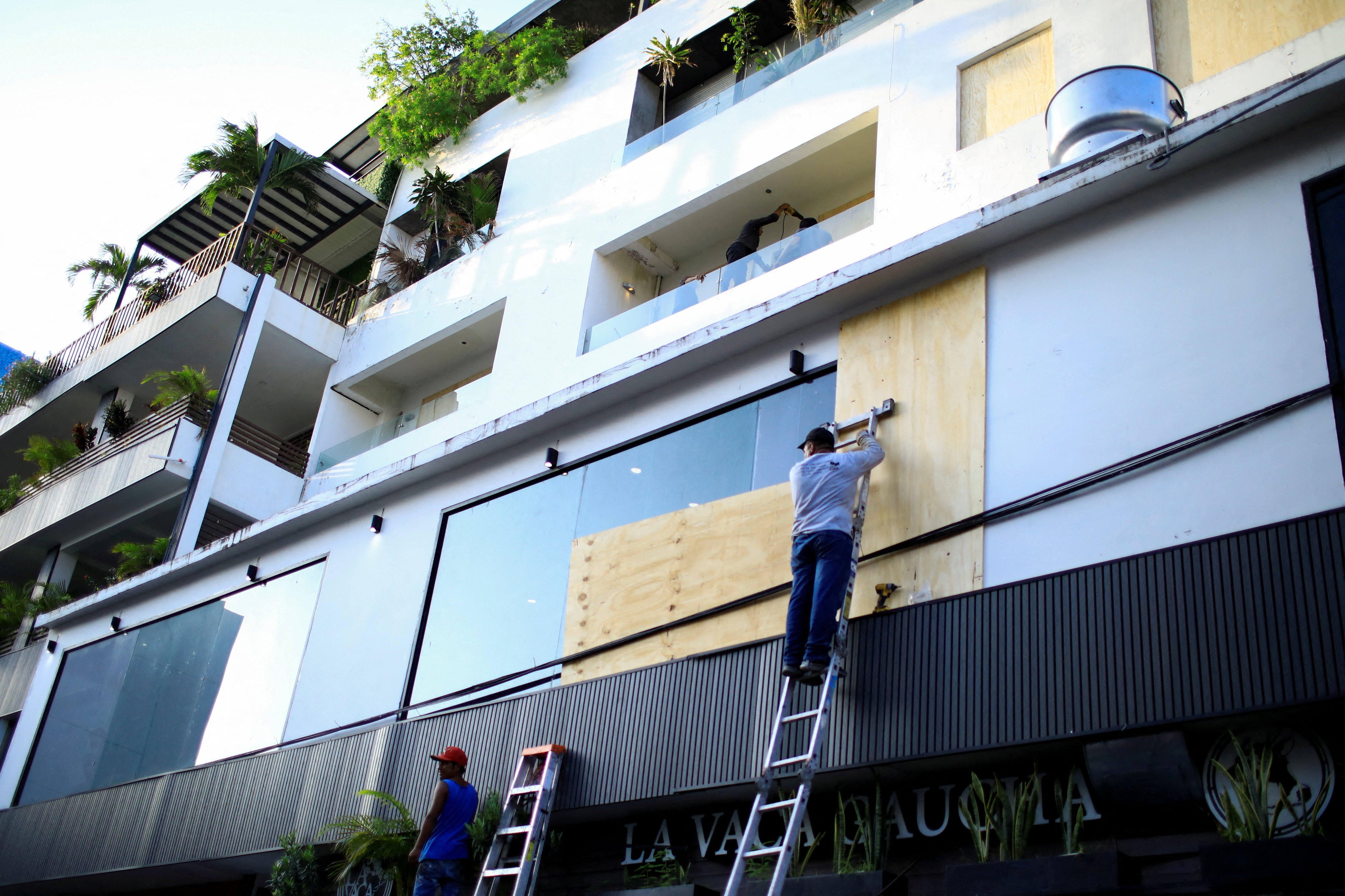 Pracownik montuje drewniane deski na oknach budynku przed huraganem Beryl w Playa del Carmen w Meksyku 3 lipca