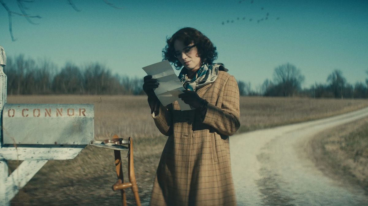 Maya Hawke jako Flannery O'Connor czytająca list, stojąc obok otwartej skrzynki pocztowej w filmie Wildcat.