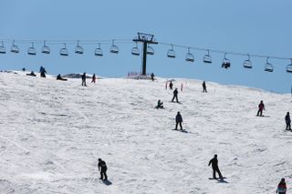 Narciarze w ośrodku Hotham Resort w Australii zjeżdżają ze stoku, w tle widać wyciągi