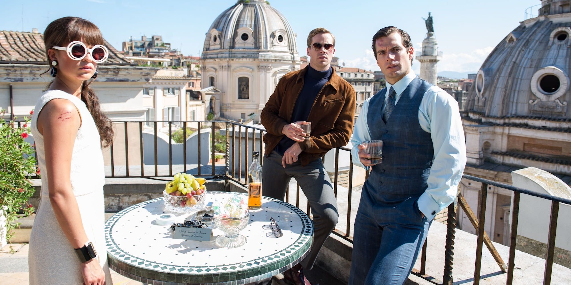 Alicia Vikander, Armie Hammer i Henry Cavill piją drinki na patio w filmie The Man From UNCLE