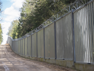 Pięciometrowy mur stalowych przęseł zwieńczony drutem kolczastym został zbudowany przez polskie władze w 2022 r. wzdłuż 186-kilometrowego odcinka granicy z Białorusią. Zdjęcie: Ingrid Prestetun/NRC