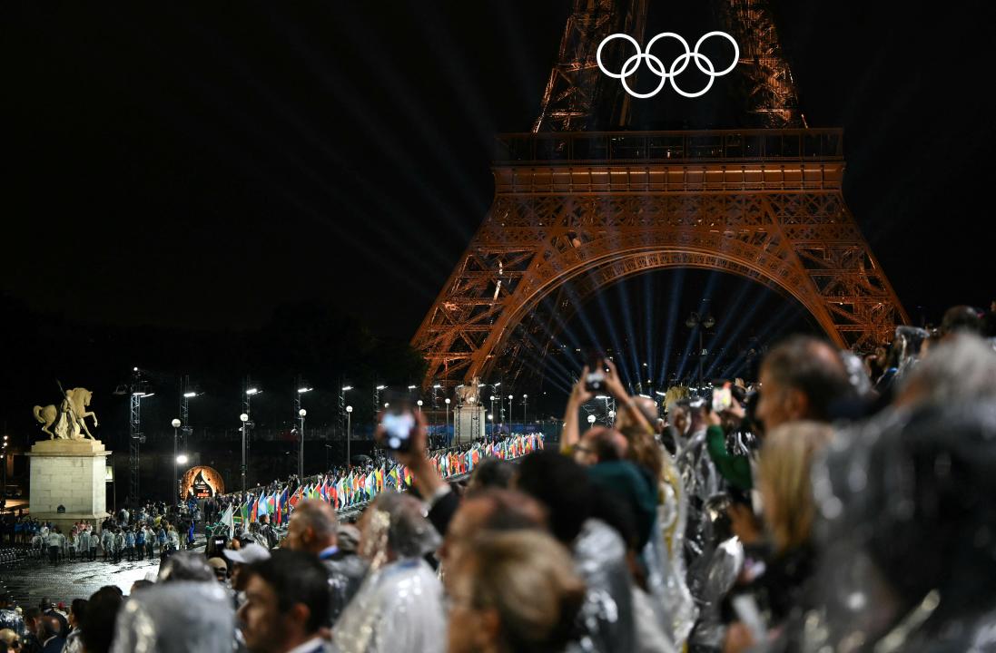 Flagi krajów uczestniczących niesione na moście Iena podczas ceremonii otwarcia Igrzysk Olimpijskich Paryż 2024 w Paryżu, 26 lipca 2024 r. (Zdjęcie: Jonathan NACKSTRAND / AFP) (Zdjęcie: JONATHAN NACKSTRAND/AFP via Getty Images)