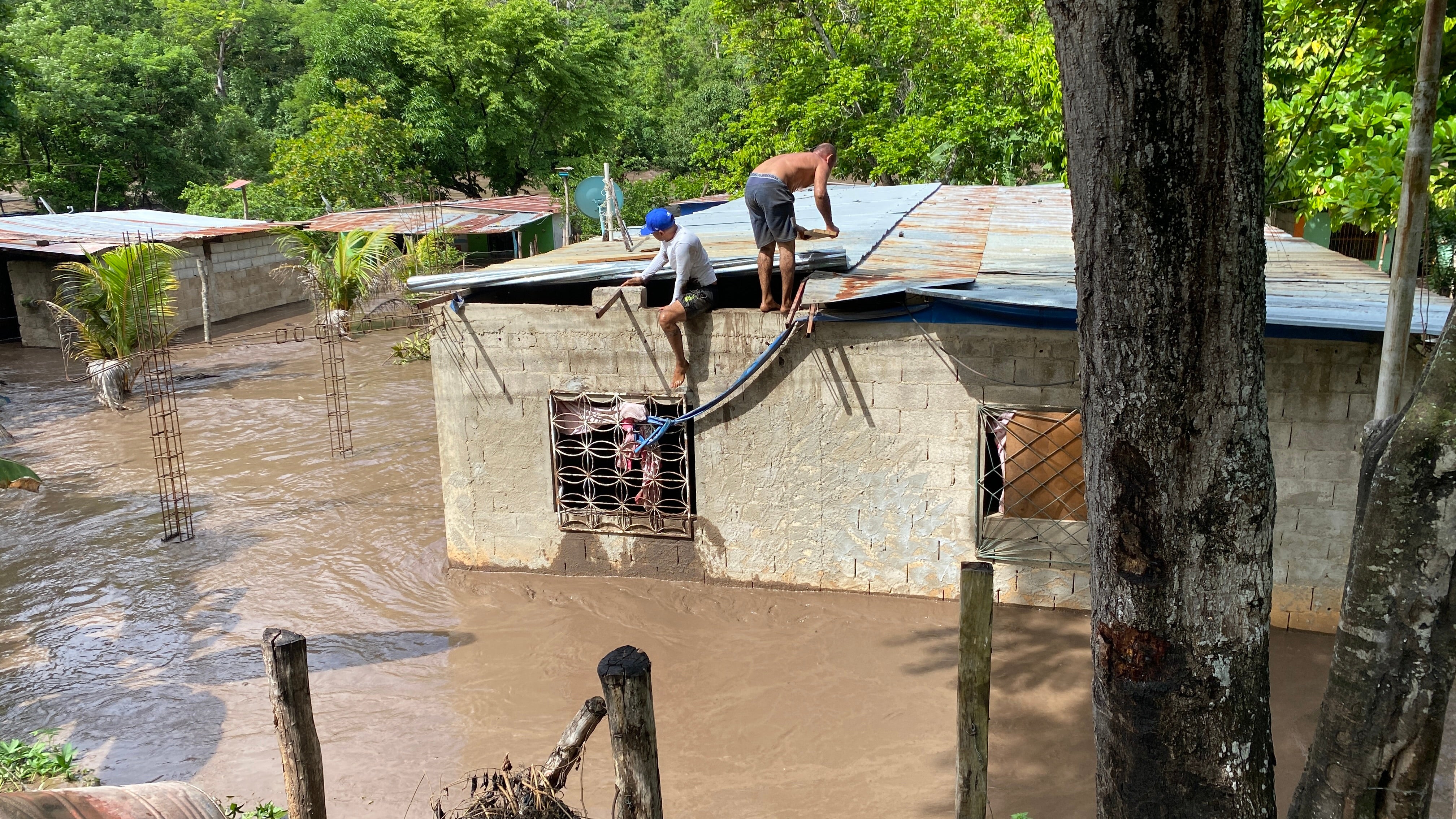 Mieszkańcy pracują nad naprawą dachu zalanego budynku w Wenezueli po przejściu huraganu Beryl przez region