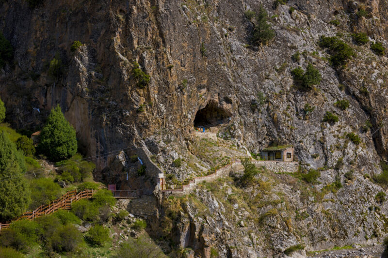 Obraz stromej ściany klifu z wąską ścieżką prowadzącą do otworu jaskini.