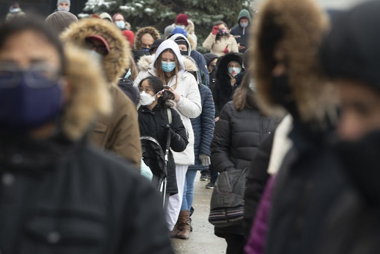 Tłum ludzi w zimowych ubraniach i maskach na twarzach