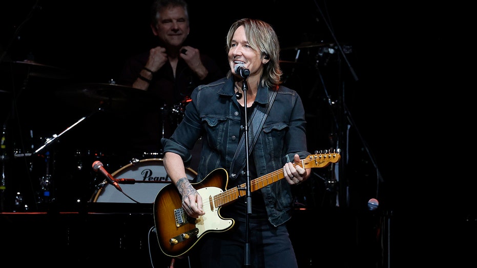 Keith Urban gra na gitarze i śpiewa do mikrofonu