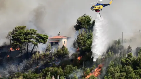 Reuters Helikopter leci i zrzuca wodę na ogień płonący w pobliżu domu