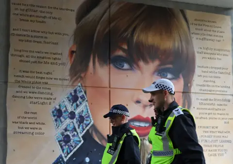 Funkcjonariusze policji przechodzą obok muralu Taylor Swift podczas wykonywania obowiązków służbowych podczas meczu piłki nożnej Community Shield na stadionie Wembley w Londynie