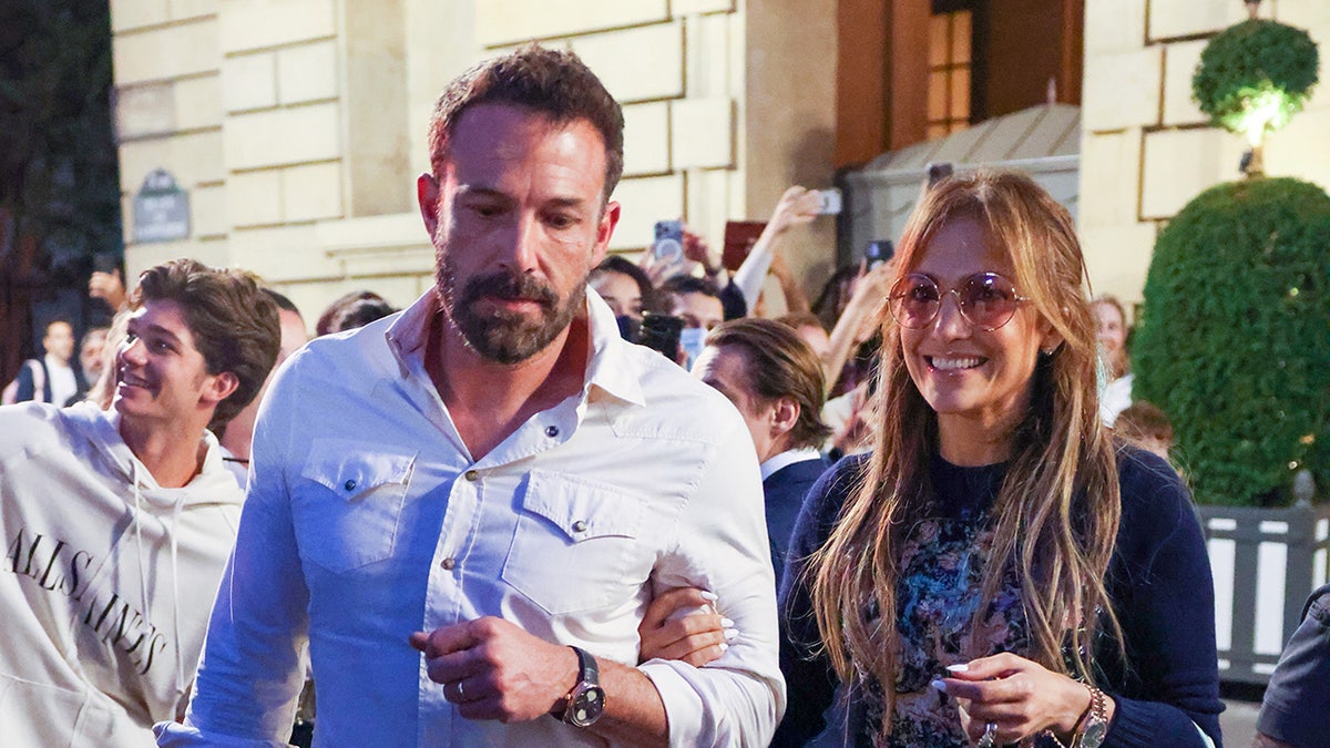 Ben Affleck wygląda poważnie, a uśmiechnięta Jennifer Lopez spaceruje po przestrzeni publicznej