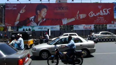 Getty Images Plakat filmu Pokkiri Tamil i ruch uliczny na drodze w Chennai w 2007 r.