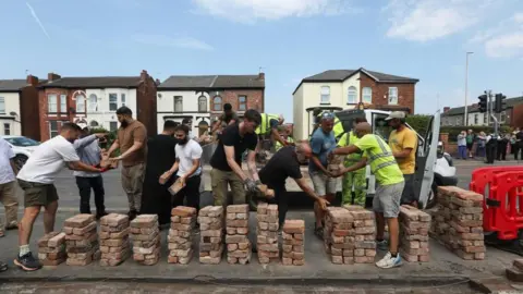 Reuters / Temilade Adelaja Wolontariusze odbudowują ogrodzenie przed meczetem Southport Islamic Society po gwałtownym proteście, który miał miejsce po czuwaniu dla ofiar ataku nożem