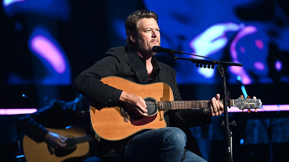 Blake Shelton siedzi na scenie z gitarą